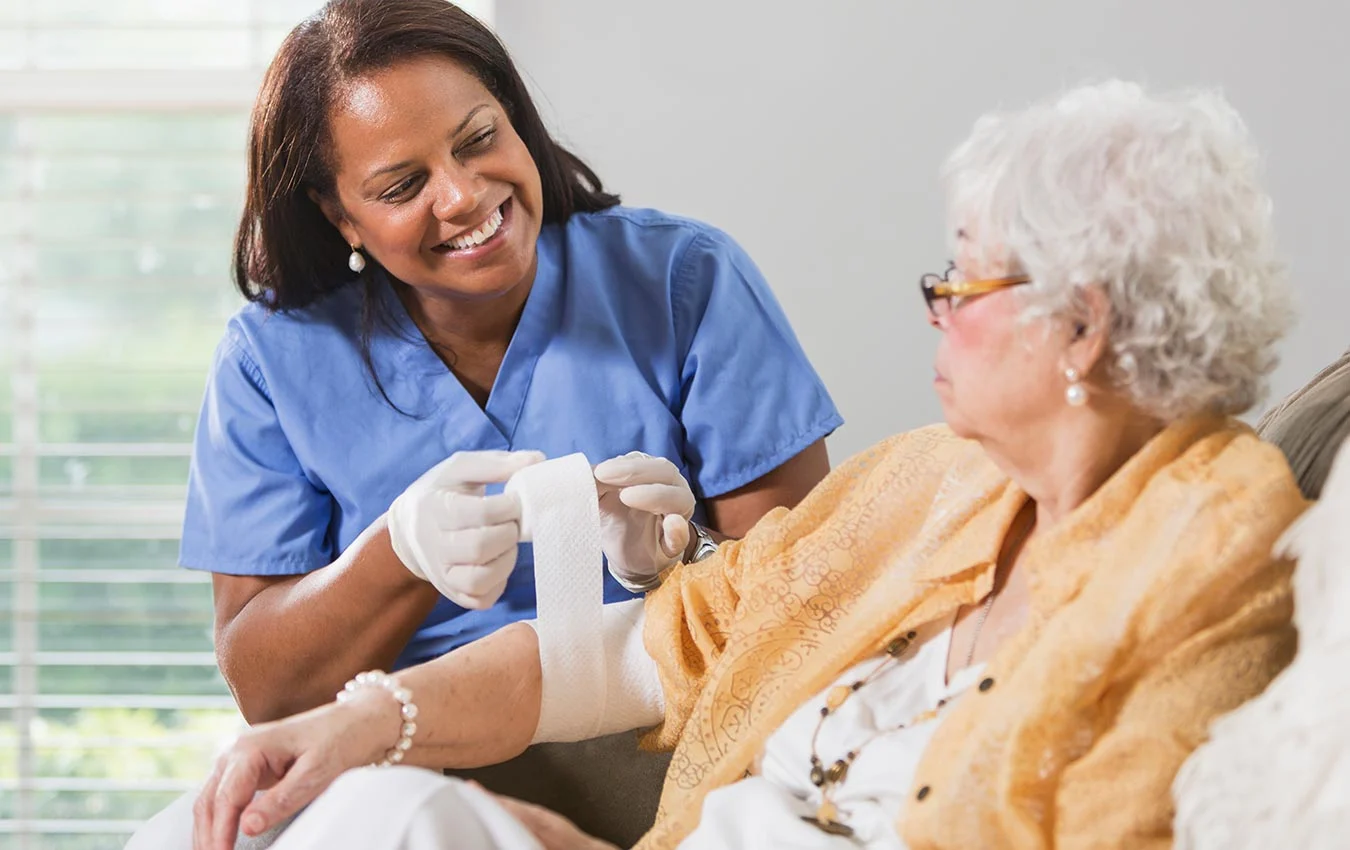 Compassionate nurse providing gentle in-home wound care to senior patient
